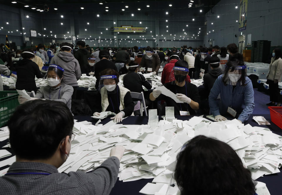 South Korean National Election Commission officials wearing masks and face shields, sort out ballots for the parliamentary election as they prepare the counting process at a ballot counting office in Seoul, South Korea, Wednesday, April 15, 2020. South Korean voters wore masks and moved slowly between lines of tape at polling stations on Wednesday to elect lawmakers in the shadows of the spreading coronavirus. (AP Photo/Lee Jin-man)