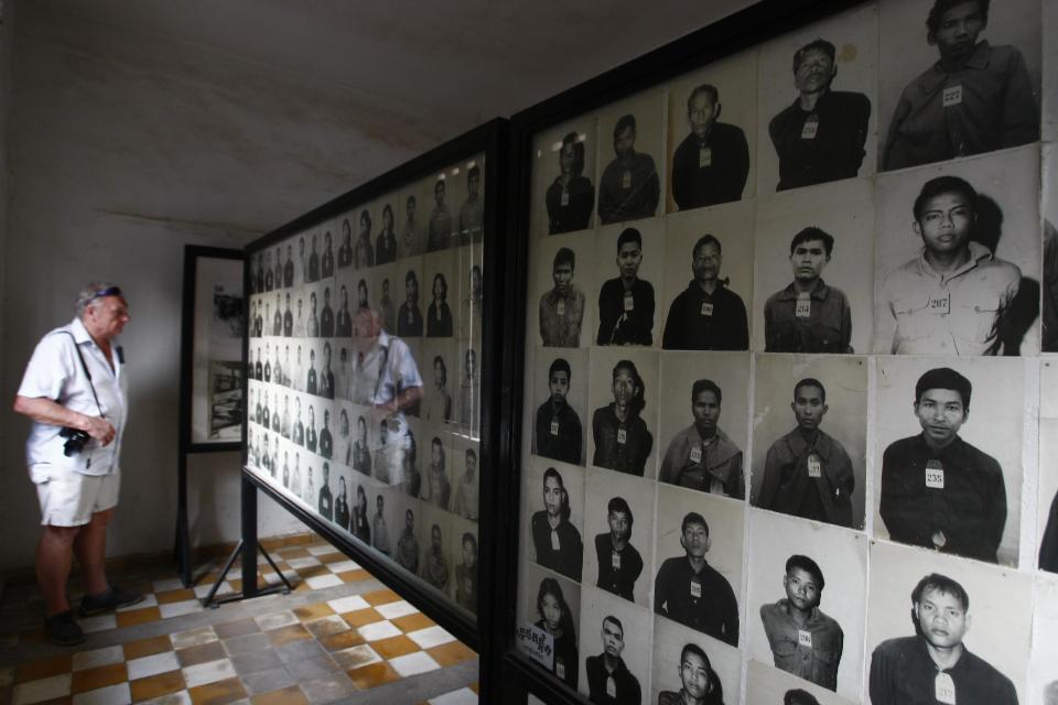 In this photo taken Thursday, Feb. 20, 2014, a tourist looks at portraits of genocide victims at the Tuol Sleng Genocide Museum, formerly the most notorious Khmer Rouge prison, in Phnom Penh, Cambodia. The office of Cambodia's most celebrated filmmaker is filled with books on the Khmer Rouge - on his desk, on the walls, in the filing cabinets and in every corner of Rithy Panh's dimly lit office are memories of his country's national tragedy. In his latest movie, the 51-year-old filmmaker focuses for the first time on his personal story of loss and tormented survival. "The Missing Picture" won an award at last year's Cannes Film Festival and is up for Best Foreign Language Film at the Oscars this weekend, marking the first time a Cambodian film has been nominated for an Academy Award. (AP Photo/Heng Sinith)