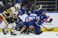 Toronto Maple Leafs forward John Tavares (91) plays the puck while falling as Pittsburgh Penguins forward Zach Aston-Reese (12) watches during the first period of an NHL hockey game Thursday, Feb. 17, 2022, in Toronto. (Nathan Denette/The Canadian Press via AP)