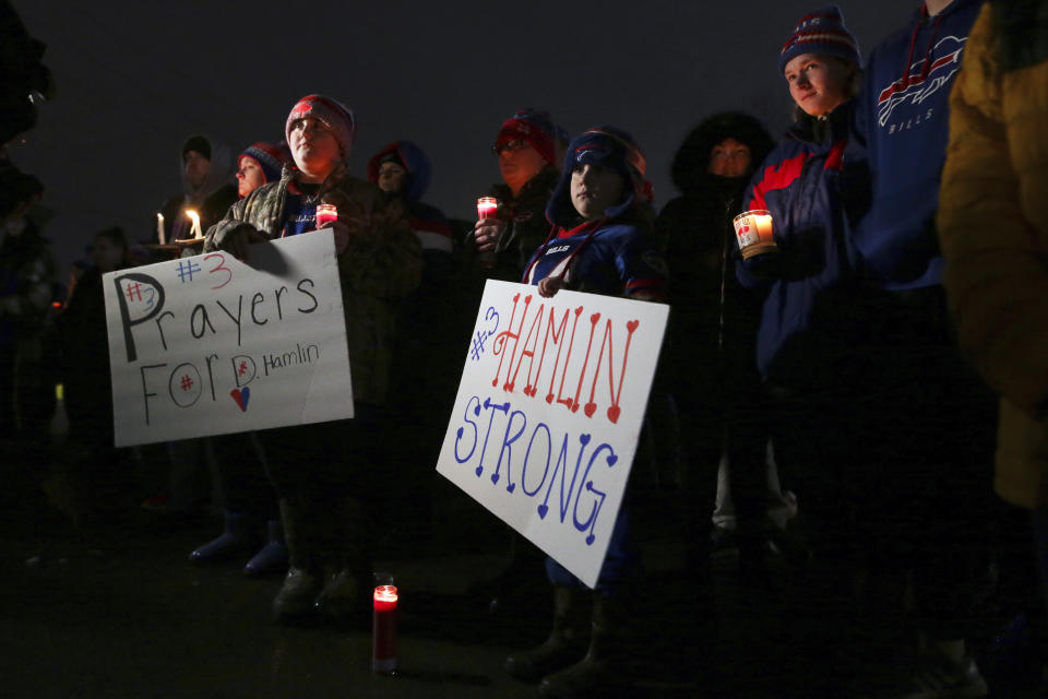FILE - Joey Wetzler, left and Johnny Wetzler, right, hold sings of support during a candlelight vigil for Buffalo Bills safety Damar Hamlin on Tuesday, Jan. 3, 2023, in Orchard Park, N.Y. The Buffalo Bills have been a reliable bright spot for a city that has been shaken by a racist mass shooting and back-to-back snowstorms in recent months. So when Bills safety Damar Hamlin was critically hurt in a game Monday, the city quickly looked for ways to support the team. (AP Photo/Joshua Bessex, File)