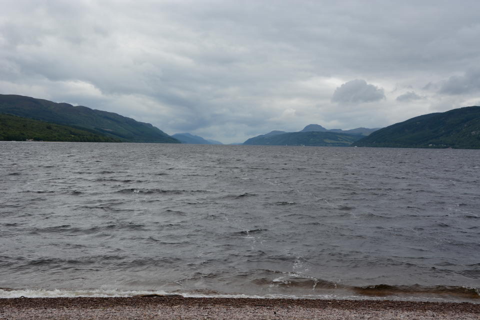 In the foreground is a small strip of pebbles, some of which has been washed by the water lapping over them.  Then we have the large expanse of Loch Ness, by volume the largest freshwater loch in Scotland, looking dark and imposing with its very murky water, due to a high peat content.  We can see the down the 23 mile length of Loch Ness, which is surrounded by hills and mountains.  The loch follows the line of the Great Glen Fault, and is reputed to hold the famous Loch Ness Monster, or Nessie as it is affectionately known.  Loch Ness is located just outside Inverness in the Highlands of Scotland