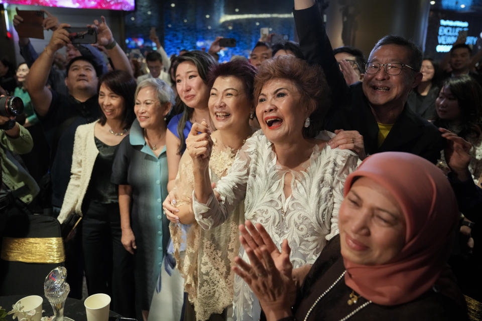 Janet Yeoh, second right, mother of Michelle Yeoh, celebrates after her daughter won in the best actress category during the 95th Academy Awards in Los Angeles, as seen in a live view event at a cinema in Kuala Lumpur, Malaysia, Monday, March 13, 2023. (AP Photo/Vincent Thian)