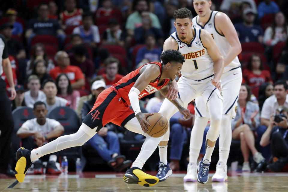 Houston Rockets guard Jalen Green, left, drives around Denver Nuggets forward Michael Porter Jr. (1) as center Nikola Jokic, right, looks on during the first half of an NBA basketball game, Tuesday, April 4, 2023, in Houston. (AP Photo/Michael Wyke)