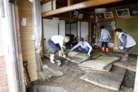 Local residents try to clean inside a house at an area flooded by Typhoon Hagibis in Marumori