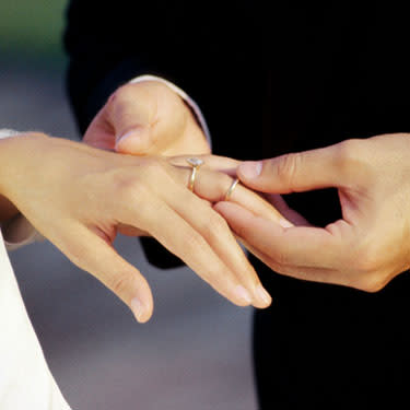 Close-up-of-a-groom-placing-a-ring-on-his-brides-finger_web