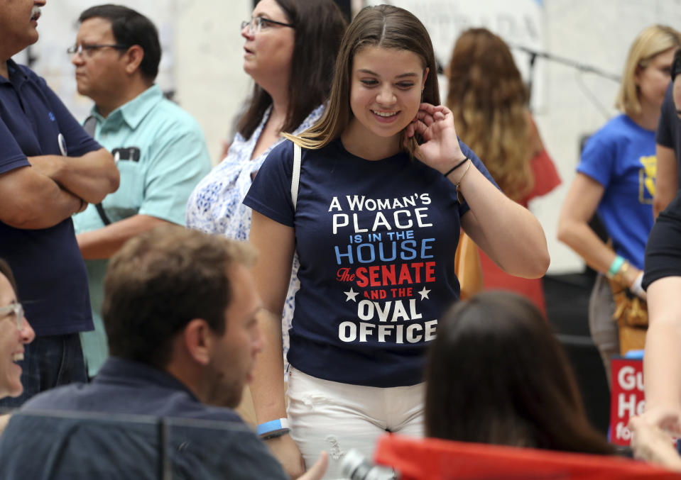 Melainey Jane Foerster, who describes herself on her business card as "just an average teenage feminist liberal environmentalist," attends a speech by New York congressional candidate Alexandria Ocasio-Cortez at a fundraiser in Los Angeles Thursday, Aug. 2, 2018. The rising liberal star startled the party when she defeated 10-term U.S. Rep. Joe Crowley in a New York City Democratic primary. Ocasio-Cortez urged a cheering crowd to work together for universal health care and free college, and not to be deterred by those who say they can't be achieved. (AP Photo/Reed Saxon)