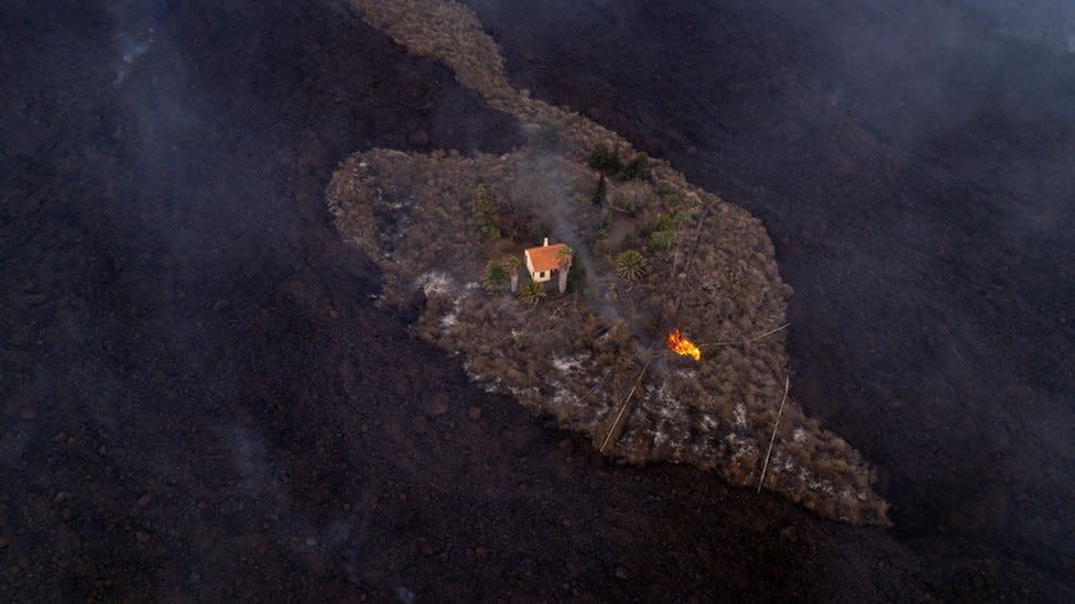 Foto aérea de una casa en pie rodeada por la lava en La Palma