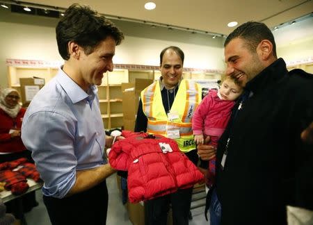 Syrian refugees are presented with a child's winter jacket by Canada's Prime Minister Justin Trudeau (L) on their arrival from Beirut at the Toronto Pearson International Airport in Mississauga, Ontario, Canada December 11, 2015. REUTERS/Mark Blinch