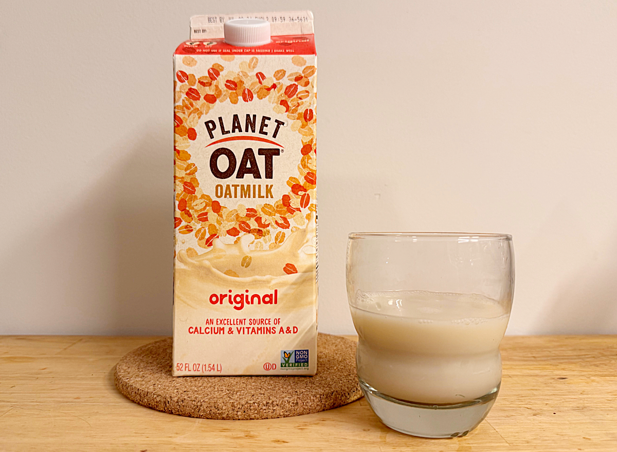 a container of planet oat oat milk next to a glass 