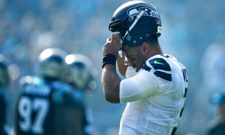 A closeup of Russell Wilson putting his Seattle Seahawks hat on.