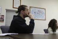 In this Nov. 12, 2019, photo, attorney Nicholas Palazzo watches a presentation by a coworker at Las Americas Immigrant Advocacy Center, in El Paso, Texas. Pushpins on the map behind him mark the homlands of the center's clients. Palazzo is one of about a dozen pro-bono lawyers in El Paso serving a population of 10,000 asylum seekers stuck in legal limbo in neighboring Ciudad Juarez, Mexico. (AP Photo/Cedar Attanasio)