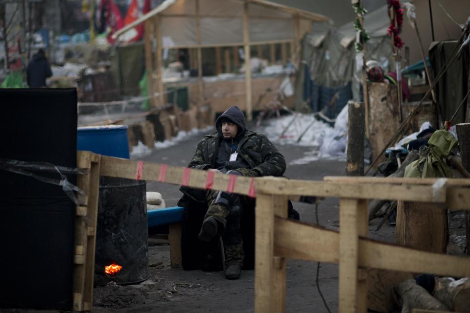 An opposition supporter guards the entrance to one of the streets leading to Kiev's Independence Square, the epicenter of the country's current unrest, Ukraine, Wednesday, Feb. 5, 2014. The mayor of a western city warned that his police would fight any troops sent in by the president. The governor of an eastern region posted an image of an opposition lawmaker beaten bloody, saying he couldn't contain his laughter. Two months into Ukraine's anti-government protests, the two sides are only moving further apart. (AP Photo/Emilio Morenatti)