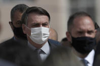 Wearing a mask to curb the spread of the new coronavirus, Brazil's President Jair Bolsonaro arrives for a ceremony to deliver affordable homes built by the government, in a neighborhood of Brasilia, Brazil, Monday, Apr. 5, 2021. (AP Photo/Eraldo Peres)