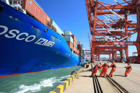 Workers help to dock a China Ocean Shipping Company (COSCO) container ship at a port in Qingdao, Shandong province, China October 19, 2018. REUTERS/Stringer/Files