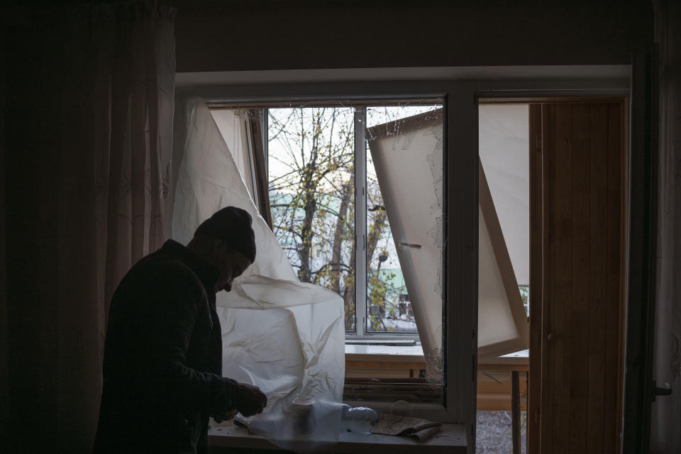 FILE - A man uses plastic to cover a broken window in his apartment following a Russian drone attack in Kyiv, Ukraine, Saturday, Nov. 25, 2023. On Monday, Dec. 4, the Biden Administration sent Congress an urgent warning about the need to approve tens of billions of dollars in military and economic assistance to Ukraine, saying that Kyiv's war effort to defend itself from Russia's invasion may grind to a halt without it. (AP Photo/Felipe Dana, File)