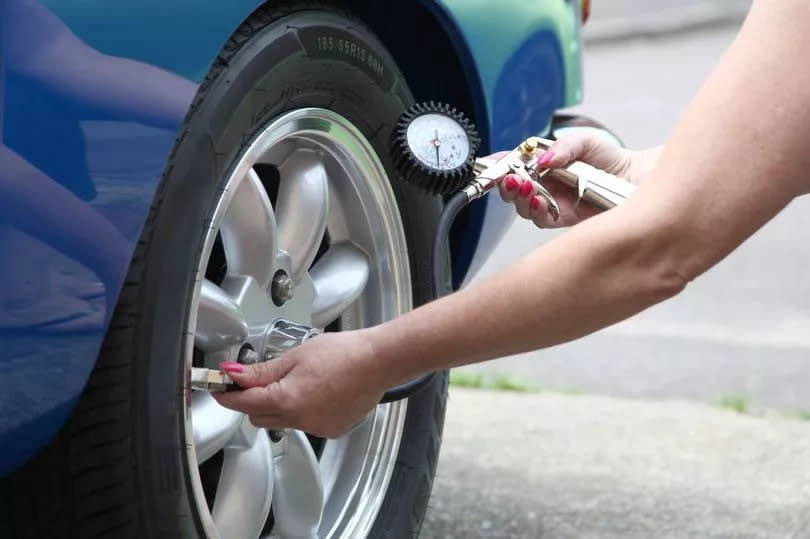 Female car maintenance using a  tyre pressure gauge to check the pressures on a classic car tyre