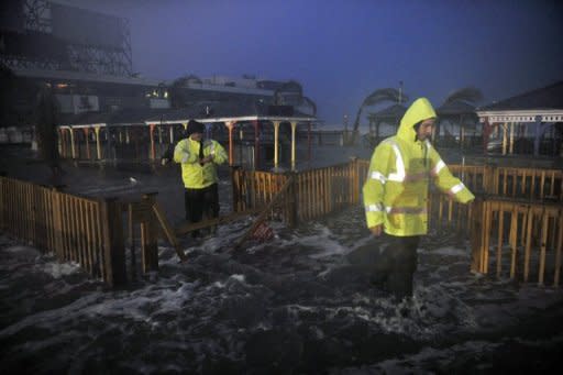 People walk through water on the beach near high tide as Sandy approaches October 29, in Atlantic City, New Jersey. Monster storm Sandy left at least 12 people dead in the United States and Canada as it swept a wall of churning sea water and driving rain onto the eastern seabord, flooding major cities and leaving chaos in its wake