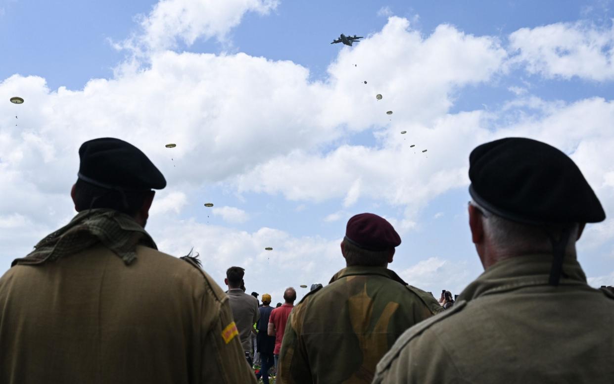 Spectators watch as UK Armed Forces parachute drop from the sky