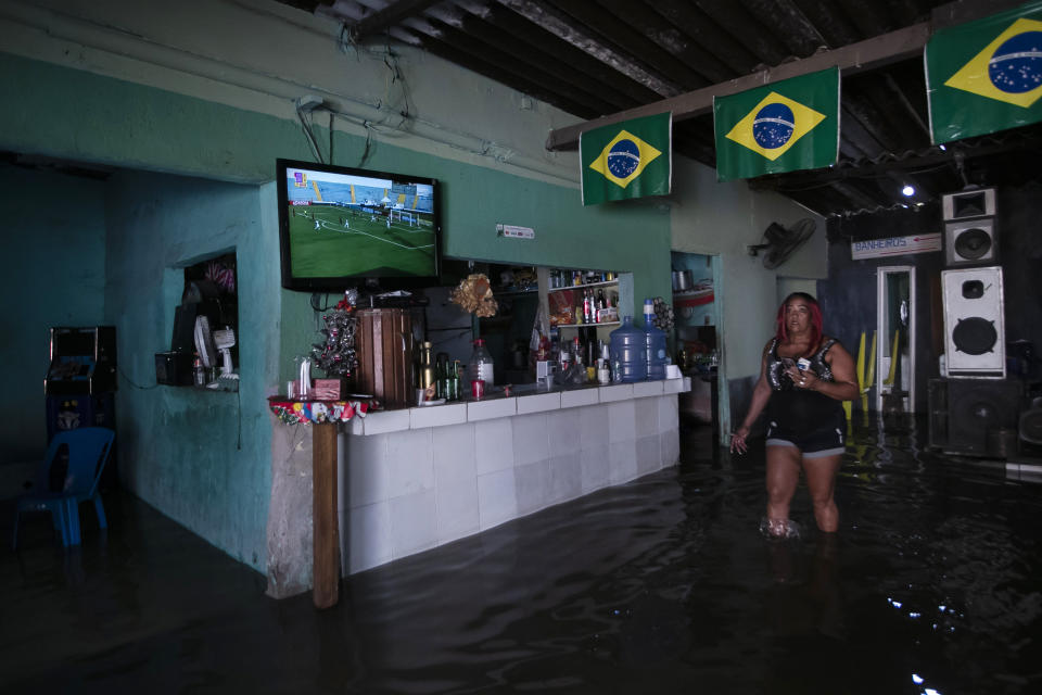 Heloisa Regina walks inside her flooded bar after deadly rainfall in Duque de Caxias, Brazil, Jan. 14, 2024. (AP Photo/Bruna Prado)