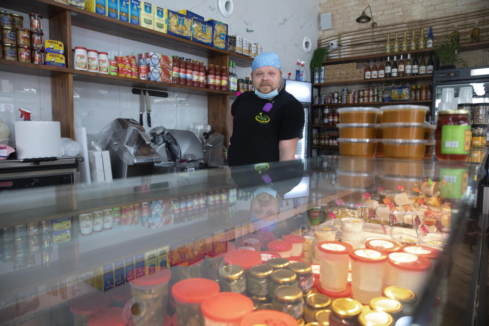 Cijay Brightman poses for a photo in Tel Aviv, Israel, Monday, July 13, 2020. A year ago, Brightman was doing sound and lighting for a Madonna performance in Israel. Now, after the coronavirus wiped out live events, he's making sandwiches, slicing cheese and serving customers at a Tel Aviv deli. (AP Photo/Sebastian Scheiner)