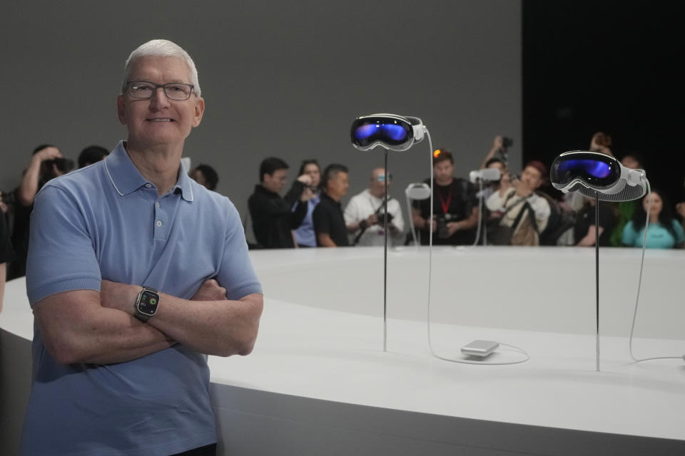 Apple CEO Tim Cook poses for photos in front of a pair of the company&#39;s new Apple Vision Pro headsets in a showroom on the Apple campus Monday, June 5, 2023, in Cupertino, Calif. (AP Photo/Jeff Chiu)