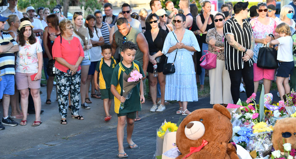 People are seen at a vigil for Kate Leadbetter, 31, and Matthew Field, 37, who were killed while walking their dogs on Australia Day, Brisbane, Wednesday, January 27, 2021. A teenager has been charged with murder after the allegedly stolen Landcruiser he was driving struck and killed the couple in Brisbane. (AAP Image/Darren England) NO ARCHIVING