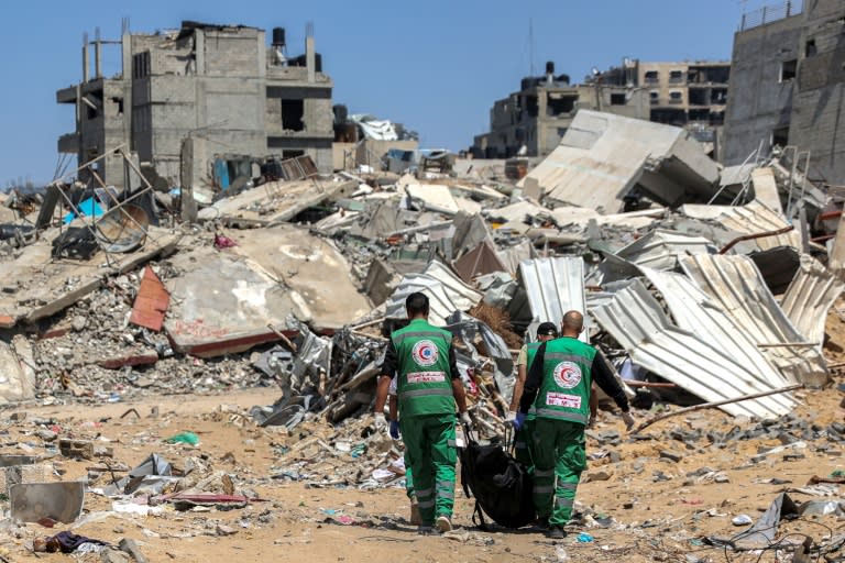 Palestinian paramedics carry away bodies of dead people uncovered in the vicinity of Al-Shifa hospital in Gaza City (-)