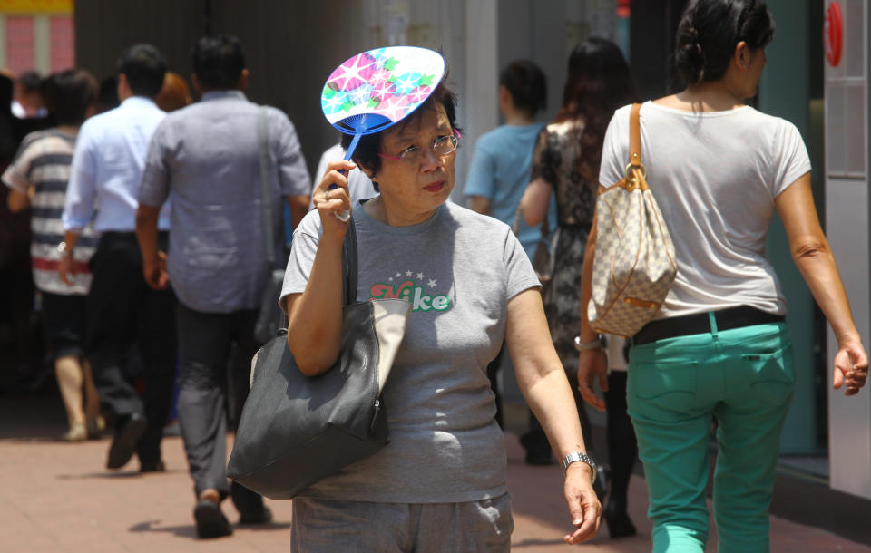 A woman uses a paper fan to protect herself from the sun during a hot day in Hong Kong. 23JUL14 (Photo by May Tse/South China Morning Post via Getty Images)