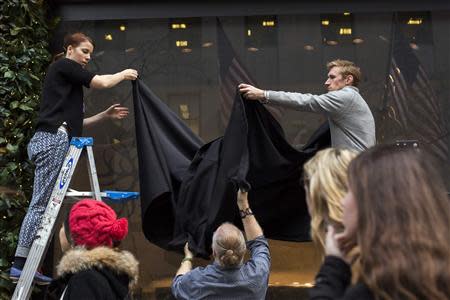 Workers hang black curtains over holiday windows before their unveiling at Saks Fifth Avenue in New York, November 22, 2013. REUTERS/Lucas Jackson