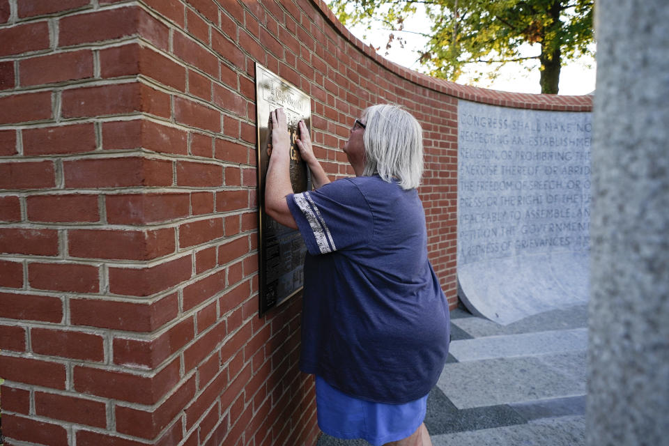 Elyzabeth Marcussen, a former community editor at the Annapolis Capital Gazette newspaper, places her hands on a plaque at the Guardians of the First Amendment memorial, which is dedicated to the victims of the newsroom shooting of 2018, Thursday, July 15, 2021, in Annapolis, Md. Marcussen left the paper three years prior to the shooting, but still had friendships with staff, including most of the people killed by Jarrod W. Ramos, the gunman which jury found criminally responsible, rejecting defense attorneys' mental illness arguments, on Thursday. (AP Photo/Julio Cortez)