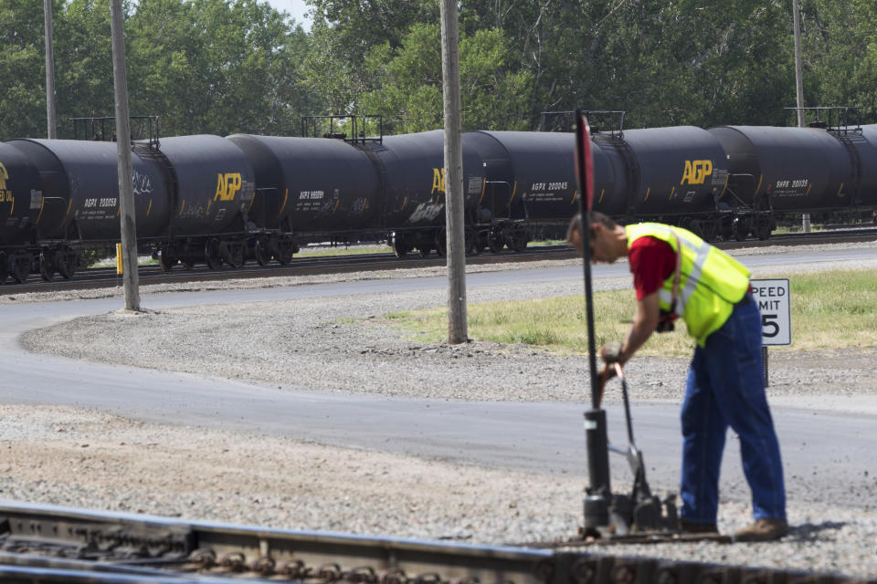 FILE - In this Aug. 8, 2012 file photo, DOT-111 and AAR-211 class rail tankers pass by on the background as a man works at the Union Pacific rail yard in Council Bluffs, Iowa. DOT-111 rail cars being used to ship crude oil from North Dakota's Bakken region are an "unacceptable public risk," and even cars voluntarily upgraded by the industry may not be sufficient, a member of the National Transportation Safety Board said Wednesday, Feb. 16, 2014. The cars were involved in derailments of oil trains in Casselton, N.D., and Lac-Megantic, Quebec, just across the U.S. border, NTSB member Robert Sumwalt said at a House Transportation subcommittee hearing. (AP Photo/Nati Harnik, File)