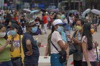 In this Saturday, May 1, 2021, photo, domestic helpers from the Philippines line up at the temporary testing center for COVID-19, in Hong Kong. Hong Kong officials have dropped a plan to make it mandatory for foreign domestic workers to be vaccinated against the coronavirus, after the move drew criticism that it was discriminatory. (AP Photo/Kin Cheung)