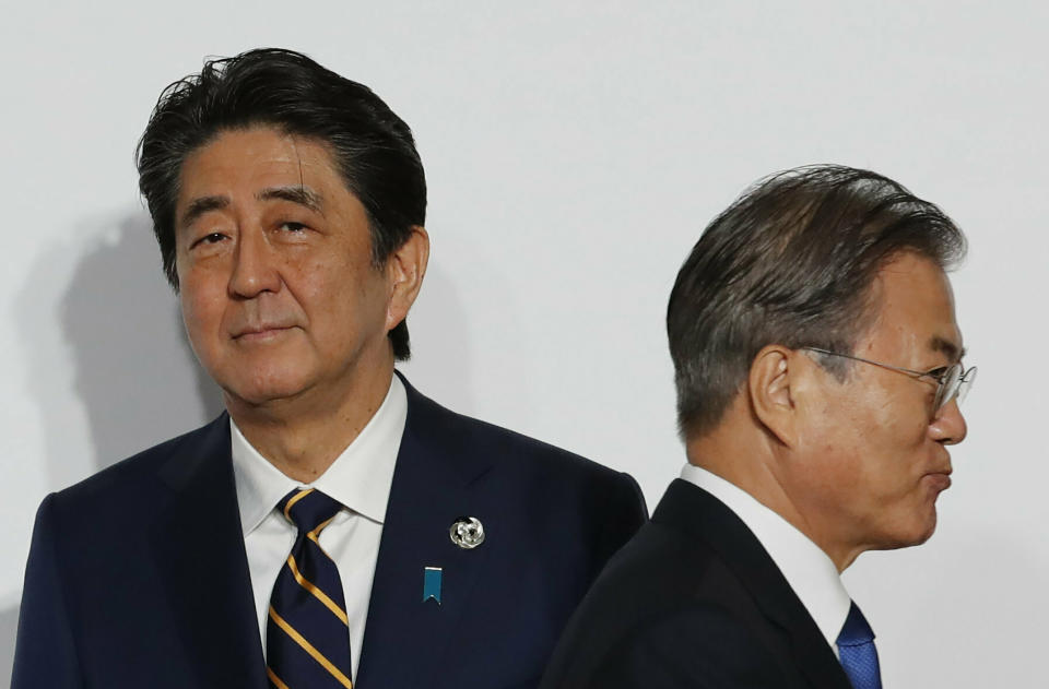 FILE - In this June 28, 2019, file photo, South Korean President Moon Jae-in, right, walks by Japanese Prime Minister Shinzo Abe upon his arrival for a welcome and family photo session at the G-20 leaders summit in Osaka, western Japan. South Korea said Thursday, Aug. 22, it is canceling an intelligence-sharing pact with Japan amid a bitter trade dispute, a surprise announcement that is likely to set back U.S. efforts to bolster mutual security cooperation with two of its most important allies in the Asian region. (Kim Kyung-Hoon/Pool Photo via AP, File)