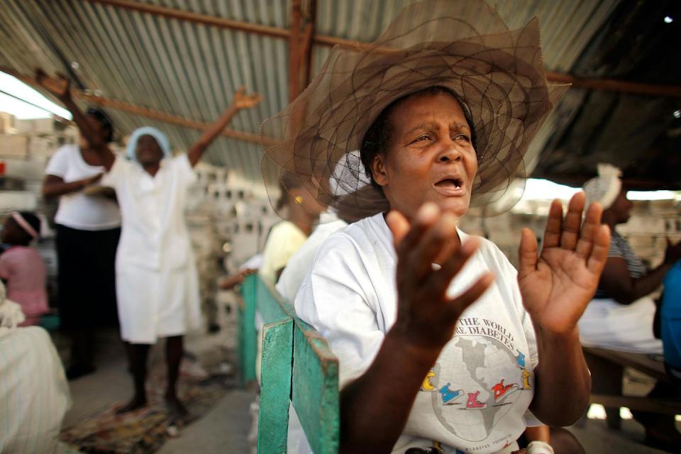 An old woman prays in an earthquake-damaged church in the Ti Ayiti neighborhood Feb. 23, 2010, in Cité Soleil, Haiti, after a Christian mob attacked a Haitian Vodou ceremony for earthquake victims. <a href="https://www.gettyimages.com/detail/news-photo/just-paces-away-from-where-a-christian-mob-attacked-a-news-photo/96989923?adppopup=true%2A%2A%2A%2A" rel="nofollow noopener" target="_blank" data-ylk="slk:Chip Somodevilla/Getty Images;elm:context_link;itc:0;sec:content-canvas" class="link ">Chip Somodevilla/Getty Images</a>