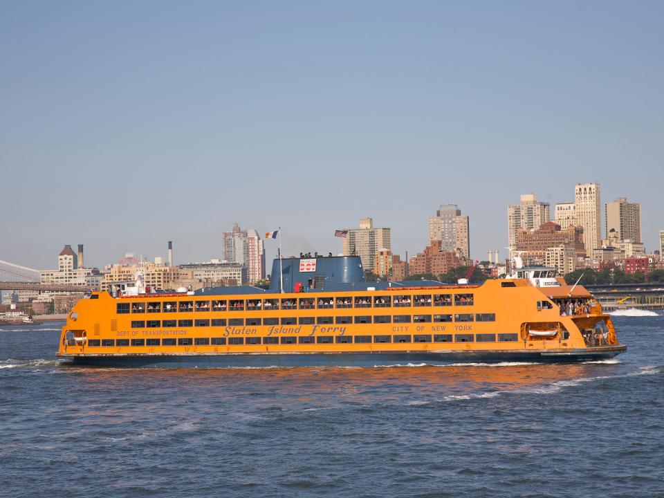 Staten Island Ferry leaving slip in Lower Manhattan with Brooklyn Heights in background, NY.