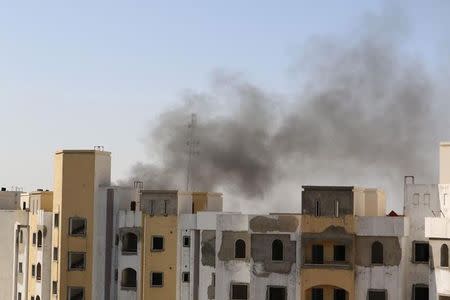 Smoke rises near buildings after heavy fighting between rival militias broke out near the airport in Tripoli July 13, 2014. REUTERS/ Hani Amara