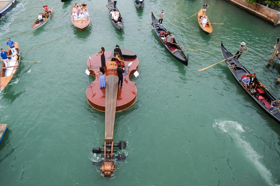 A string quartet plays onboard a violin-shaped boat, titled "Violin of Noah."