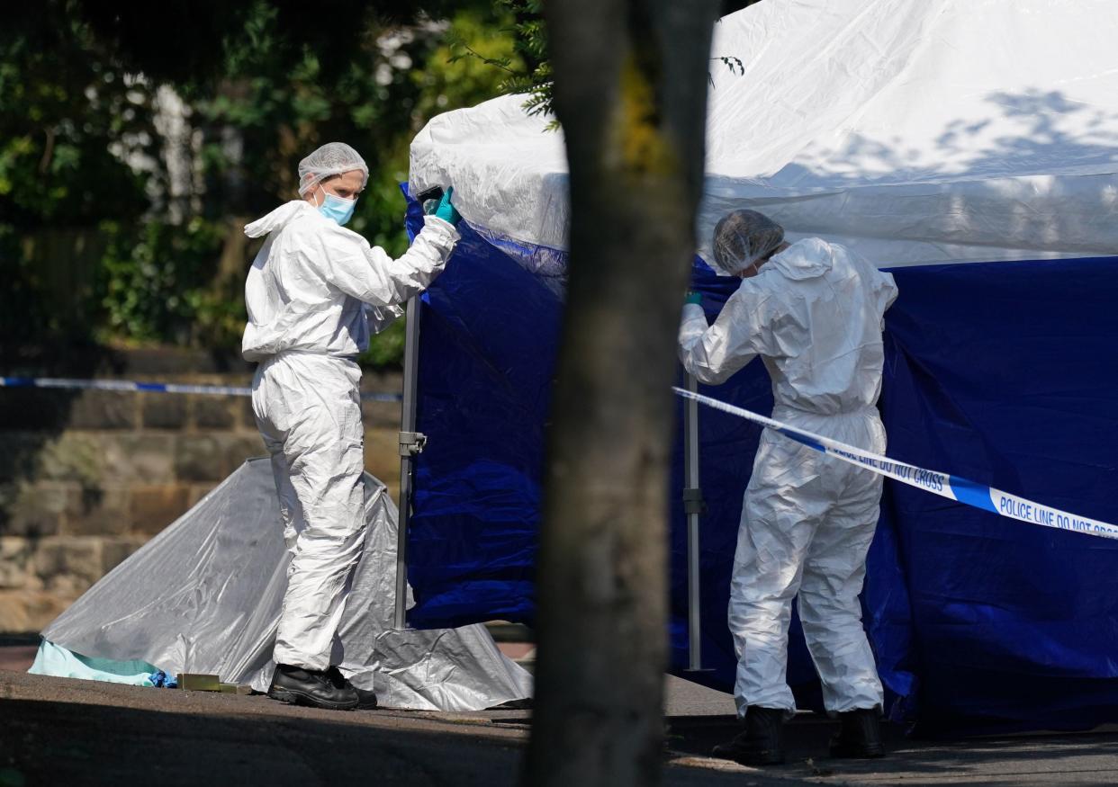 Police forensics officers erect a forensic tent on Magdala road (PA)