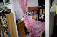 Hermes Soto plays with a curtain at his house in Mexico City