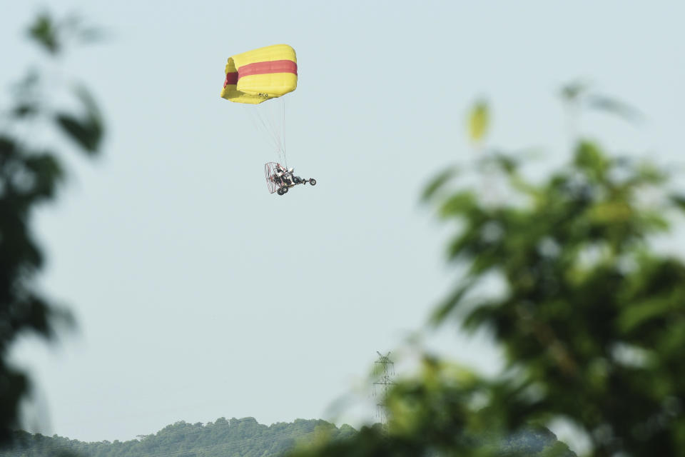 A worker in a powered parachute searches for a runaway leopard in Hangzhou in eastern China's Zhejiang province Sunday, May 9, 2021. A search for the last of three leopards that escaped from a safari park in eastern China was ongoing, authorities said Monday, May 10, 2021 as the park came under fire for concealing the breakout for nearly a week. (Chinatopix via AP)