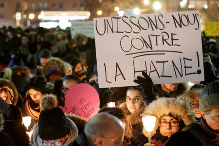 A woman holds a sign reading "lets unite against hate!" as people attend a vigil in support of the Muslim community in Montreal, Quebec, January 30, 2017. REUTERS/Dario Ayala