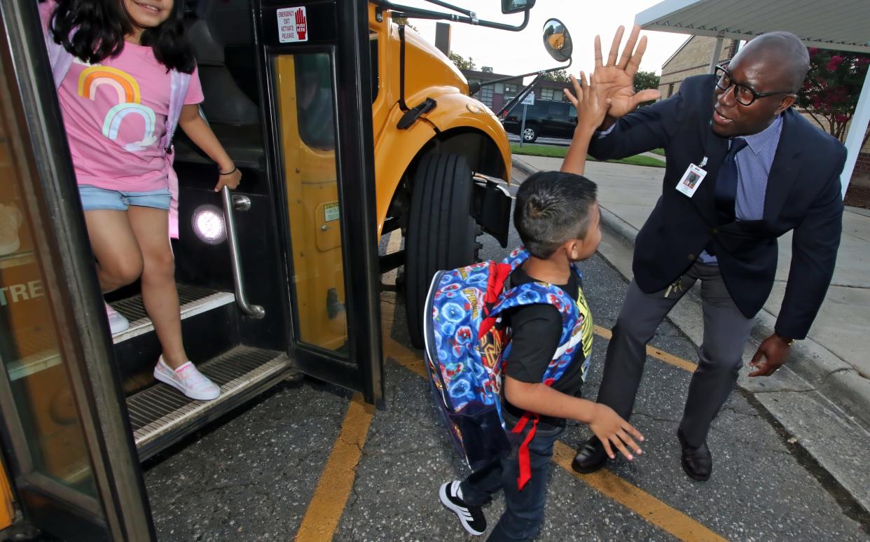 Principal Garey Coke greets students with high fives as they get off their bus early Wednesday morning, August 16, 2023, on the first day of school at Lingerfeldt Elementary in Gastonia.