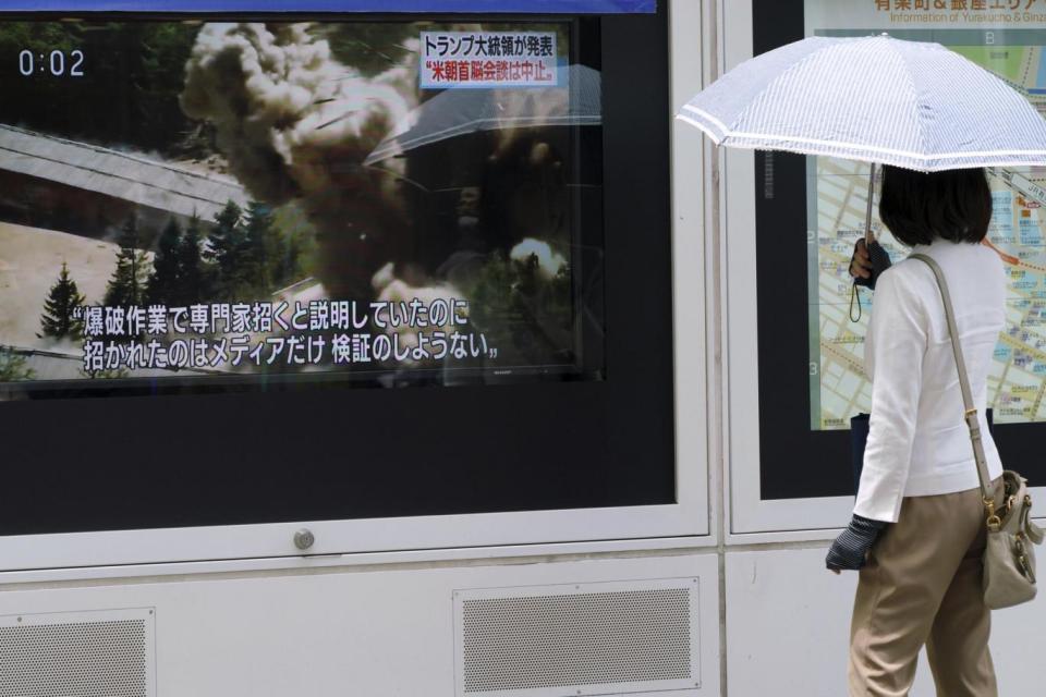 A woman stands near a TV screen showing an image of the dismantling of North Korea's Punggye-ri nuclear test site during a news program in Tokyo (AP)