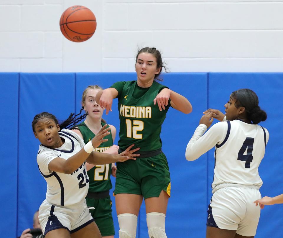 Medina's Olivia Klanac, center, makes a pass between Hoban guard Niera Stevens, left, and Makenzie Grant during the first half of a Division I district final, Friday, March 1, 2024, in Ravenna.