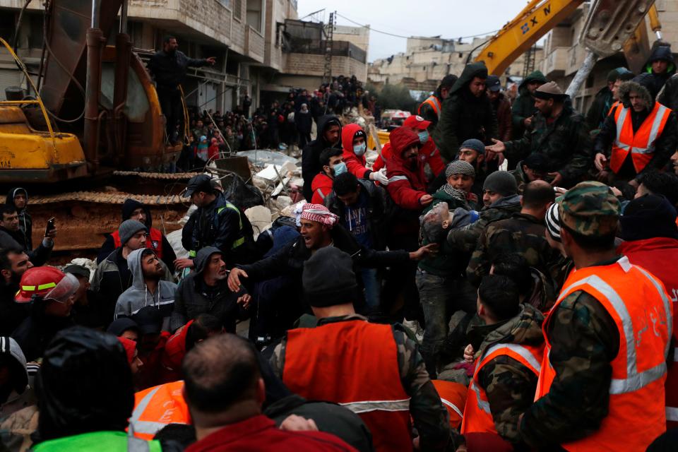 Civil defense workers and security forces carry an earthquake victim as they search through the wreckage of collapsed buildings in Hama, Syria, Monday, Feb. 6, 2023.