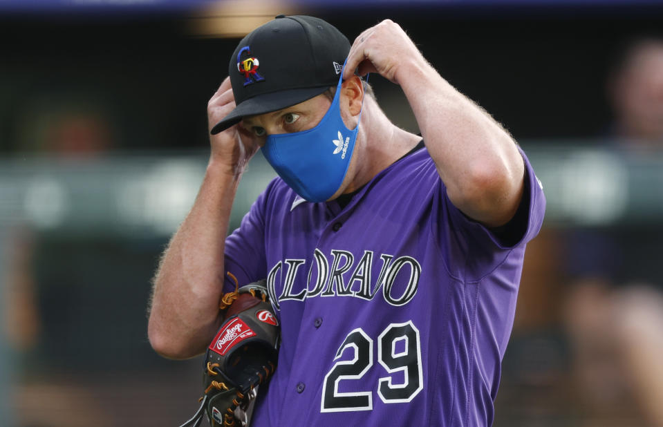 Colorado Rockies relief pitcher Bryan Shaw puts on his face mask after taking part in drills during the team's baseball practice in Coors Field, Friday, July 10, 2020, in Denver. (AP Photo/David Zalubowski)