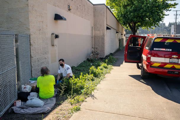 PHOTO: Gabe DeBay, Medical Services Officer with the Shoreline Fire Department, checks on a homeless man during the hottest part of the day, July 26, 2022 in Shoreline, Wa.  (David Ryder/Getty Images)