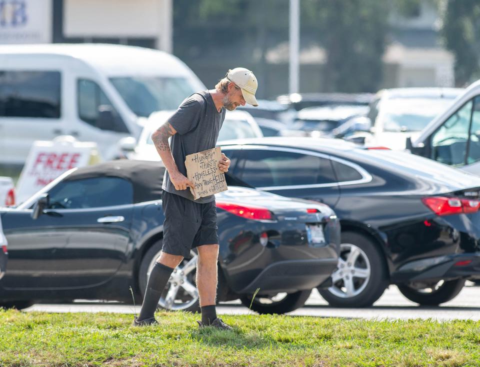 A person panhandles along Brent Lane near North Davis Highway in Escambia County on Monday, Sept. 11, 2023.