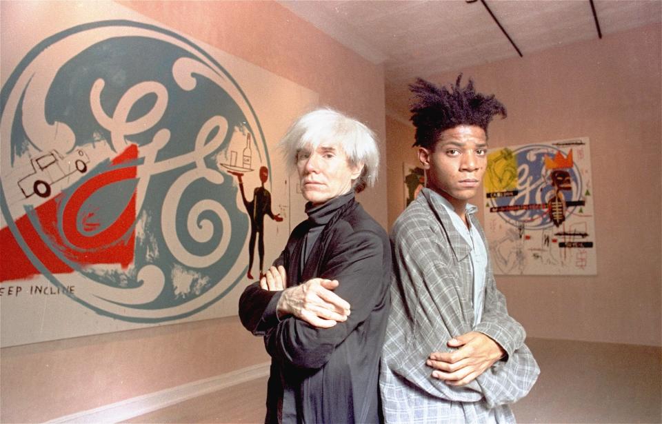 Andy Warhol and Jean-Michel Basquiat in front of their collaborative paintings at the Tony Shafrazi Gallery in SoHo in 1985. (Photo: Richard Drew/AP)