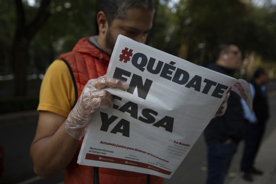 A man reads a newspaper with the Spanish headline: "Stay home now" in Mexico City, Wednesday, April 1, 2020. Mexico's government has broadened its shutdown of "non essential activities," and prohibited gatherings of more than 50 people as a way to help slow down the spread of COVID-19. The one-month emergency measures will be in effect from March 30 to April 30. (AP Photo/Fernando Llano)